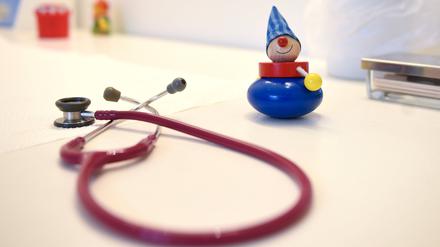 Ein Stethoskop und Kinderspielzeug liegen in einer Kinderarztpraxis auf einem Tisch.