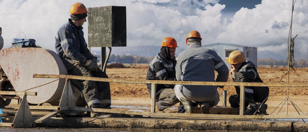 Arbeiter reparieren ein Teil einer Bohranlage zur Gewinnung von Erdöl.