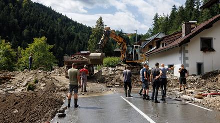Menschen säubern eine Straße und ein Haus im slowenischen Raduha vom Hochwasserschutt.
