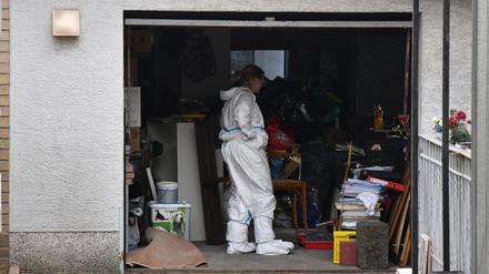Beamte durchsuchen eine Garage im Umfeld eines Gartens in Homburg im Saarland, in dem eine Leiche gefunden wurde.