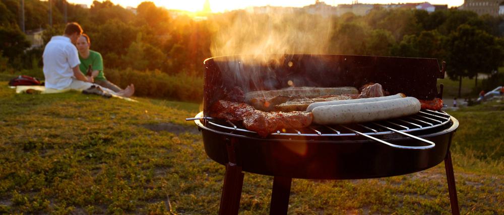 Grill mit Würstchen und Fleisch lässt verführerische Dämpfe in die Luft steigen.