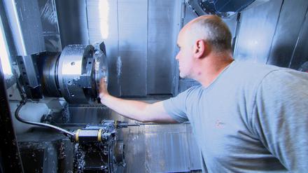 Arbeiter beim Check an einer vollautomatischen Fäsmaschine - die hohen Energiekosten bringen die deutsche Industrie in Bedrängnis.