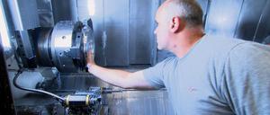 Arbeiter beim Check an einer vollautomatischen Fäsmaschine - die hohen Energiekosten bringen die deutsche Industrie in Bedrängnis.