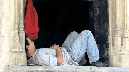Ein Handwerker macht Siesta auf einer Fensterbank in Palma de Mallorca in Spanien.