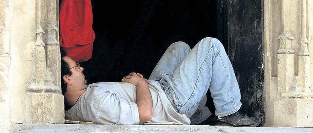 Ein Handwerker macht Siesta auf einer Fensterbank in Palma de Mallorca in Spanien.
