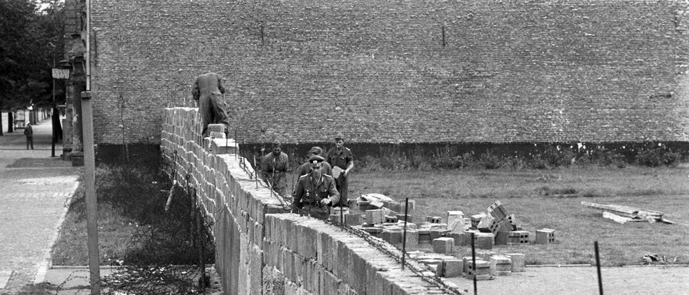 ARCHIV - Volkspolizisten und Arbeiter der DDR beim Errichten der Berliner Mauer am 06.10.1961 im Norden Berlins an der Grenze zum westberliner Bezirk Reinickendorf. Der US-Geheimdienst NSA hatte nach bislang geheimen Dokumenten bereits vorab Informationen über den geplanten Bau der Berliner Mauer. Foto: dpa (zu dpa "Geheimdokumente: NSA warnte früh vor Mauerbau in Berlin" vom 26.09.2013) +++ dpa-Bildfunk +++