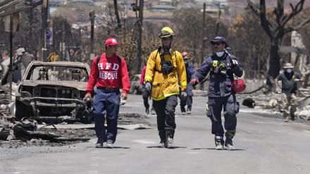 Mitglieder eines Such- und Rettungsteams gehen in Lahaina, Hawaii, eine Straße entlang. 