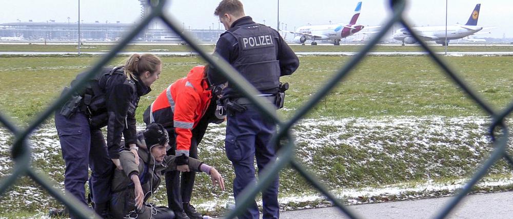 Zwei Beamte der Bundespolizei und ein Sicherheitsmitarbeiter stehen am 8.12.2022 mit einem sichergestellten Bolzenschneider an einem Zaun am BER-Flughafen. 