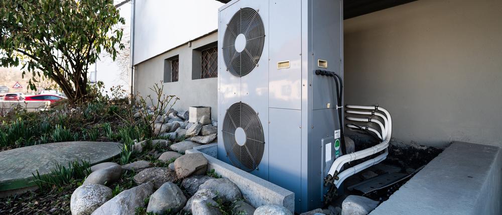 Die Lüftungsanlage einer Wärmepumpe steht vor einem Wohnhaus.