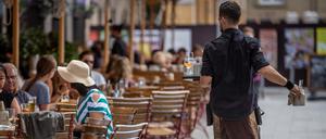 Eine Servicekraft bedient im Außenbereich eines Restaurants die Gäste.