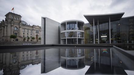 Das Paul-Löbe-Haus (M.) des Deutschen Bundestages spiegelt sich neben dem Reichstagsgebäude (l.) in einer Glasfläche.