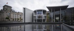 Das Paul-Löbe-Haus (Mitte) des Deutschen Bundestages spiegelt sich neben dem Reichstagsgebäude (links) in einer Glasfläche.