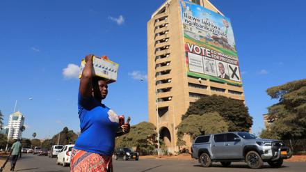 Eine Frau läuft in Harare an einem Haus mit einem riesigen Wahlplakat vorbei.