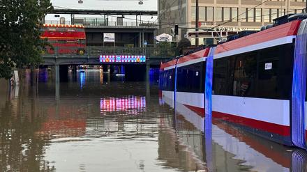 Eine Straßenbahn steht in einer überschwemmten Straße an einer Unterführung in Nürnberg.