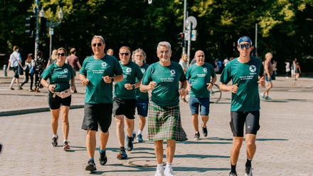 Die Läufer um John McGurk (M.) des „Friedenslaufes“ kommen am Brandenburger Tor an. 