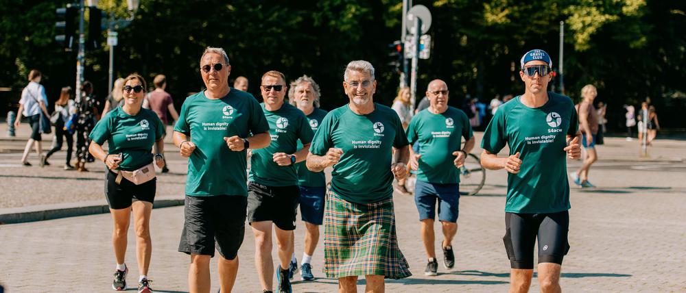 Die Läufer um John McGurk (M.) des „Friedenslaufes“ kommen am Brandenburger Tor an. 