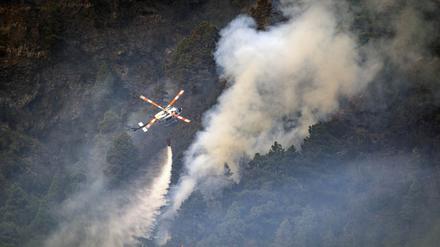 Ein Hubschrauber wirft Wasser auf die Flammen.