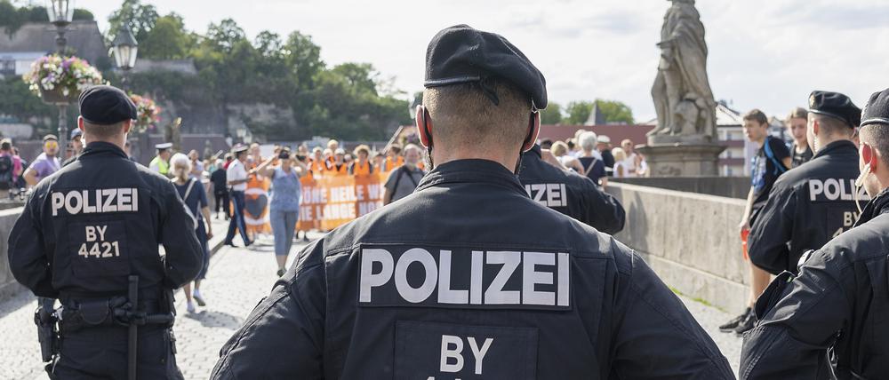 Polizisten stoppen Menschen, die unter dem Namen Letzte Generation in einem Protestmarsch über die alte Mainbrücke ziehen, auf dem Weg in die Innenstadt.