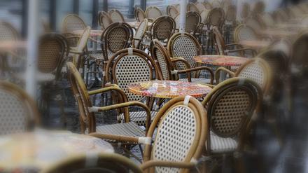 Im Regen stehen leere Tische und Stühle am Sonntag vor Cafes und Restaurants.