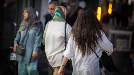 Eine Frau läuft in Teheran im Iran mit offenen Haaren am Abend eine Straße entlang. 