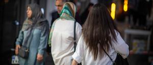 Eine Frau läuft in Teheran im Iran mit offenen Haaren am Abend eine Straße entlang.