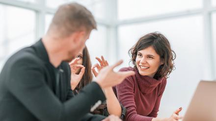 Eine Gruppe junger Menschen diskutiert vor einem Laptop.