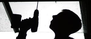 Ein Auszubildender im Tischlerhandwerk bohrt am 19.08.2014 in Hannover (Niedersachsen) ein Loch in ein Brett.