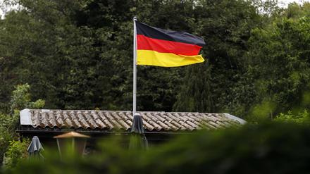 Eine Deutschlandfahne weht in einer Kleingartenanlage.