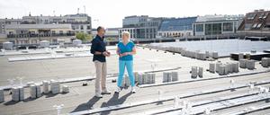Verwaltungsdirektor Guido Hermann und Wirtschaftssenatorin Giffey auf dem Dach des Friedrichstadtpalastes zwischen Trägern für die neue Solaranlage.