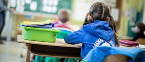 Schülerinnen und Schüler einer Grundschule sitzen mit Abstand in ihrem Klassenraum. 