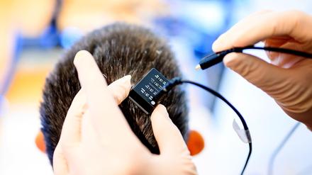 UCSF clinical research coordinator Max Dougherty connects a neural data port in the study participant’s head to the speech prosthesis system on Monday, May 22, 2023, in El Cerrito, Calif as part of Dr. Edward Chang’s study of speech neuroprostheses.