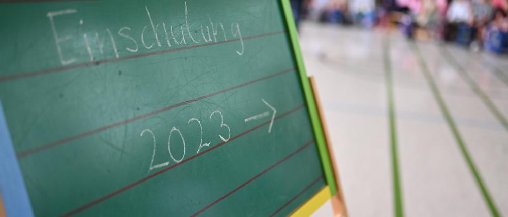 Einschulung 2023· steht an einer Tafel während einer Einschulungsfeier von Erstklässlerinnen und Erstklässlern.