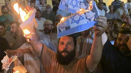 27.08.2023, Libyen, Tripolis: Menschen verbrennen Fotos, die den israelischen Außenminister Eli Cohen und seine libysche Amtskollegin Nadschla al-Mankusch zeigen.