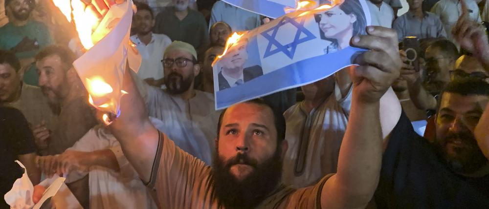 27.08.2023, Libyen, Tripolis: Menschen verbrennen Fotos, die den israelischen Außenminister Eli Cohen und seine libysche Amtskollegin Nadschla al-Mankusch zeigen.