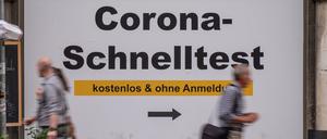 Passanten gehen in der Fußgängerzone in der Innenstadt an einem Plakat mit der Aufschrift ·Corona-Schnelltest - kostenlos und ohne Anmeldung· vorbei. (Symbolbild)