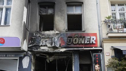 Ein Polizist steht vor einem ausgebrannten Döner-Imbiss in der Uhlandstraße.