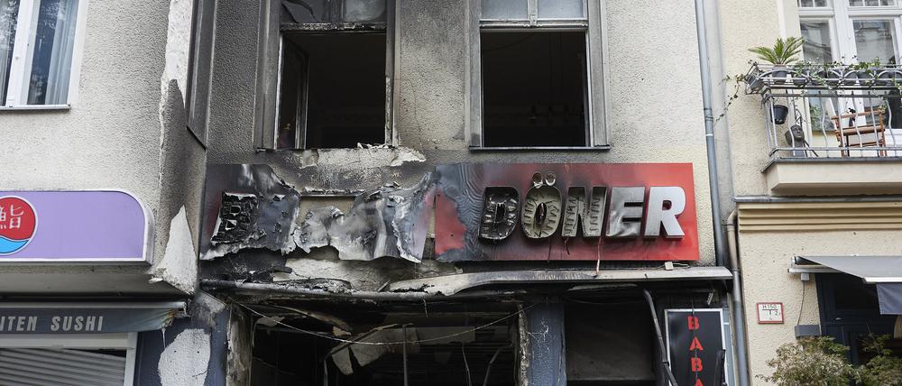Ein Polizist steht vor einem ausgebrannten Döner-Imbiss in der Uhlandstraße.