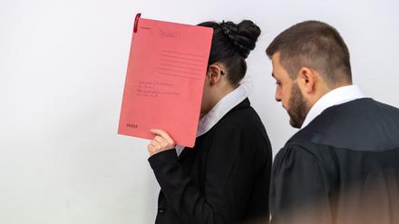 ARCHIV - 04.07.2019, Bayern, München: Die Angeklagte Jennifer W., die sich der Terrormiliz Islamischer Staat (IS) im Irak angeschlossen haben soll, hält sich beim Betreten des Gerichtssaals einen roten Aktendeckel vors Gesicht. Rechts steht ihr damaliger Anwalt Ali Aydin. Im Oktober 2021 war sie zu 10 Jahren Haft verurteilt worden. Ihr wurde unter anderem angelastet, ein fünf Jahre altes Mädchen als Sklavin gehalten und zugesehen zu haben, wie es verdurstete. Der Prozess wurde nach einer Revision vom Bundesgerichtshof an das OLG zurückverwiesen zu einer Entscheidung über das Strafmaß. Am Dienstag soll nun das Urteil im Wiederaufnahmeverfahren gesprochen werden. (zu dpa: «Urteil gegen IS-Rückkehrerin wegen Tod eines jesidischen Mädchens») Foto: Peter Kneffel/dpa +++ dpa-Bildfunk +++