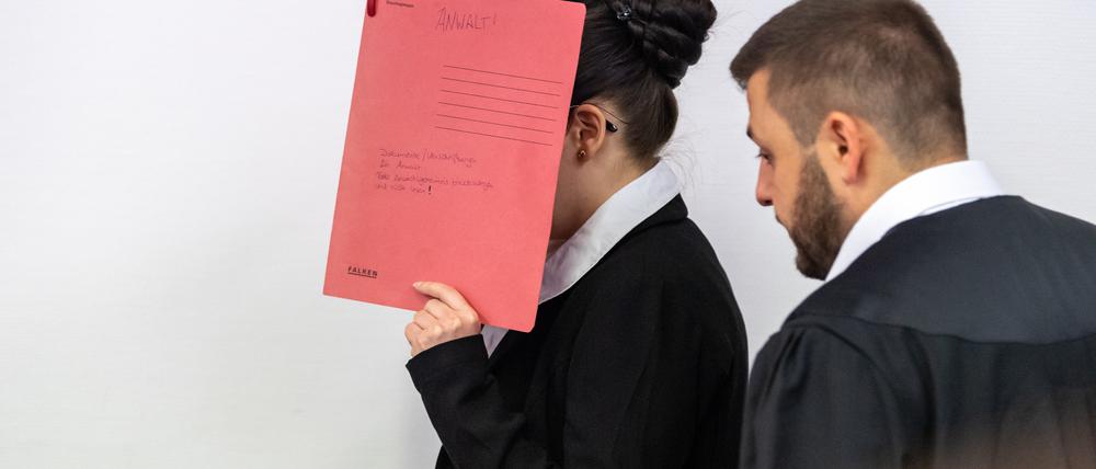 ARCHIV - 04.07.2019, Bayern, München: Die Angeklagte Jennifer W., die sich der Terrormiliz Islamischer Staat (IS) im Irak angeschlossen haben soll, hält sich beim Betreten des Gerichtssaals einen roten Aktendeckel vors Gesicht. Rechts steht ihr damaliger Anwalt Ali Aydin. Im Oktober 2021 war sie zu 10 Jahren Haft verurteilt worden. Ihr wurde unter anderem angelastet, ein fünf Jahre altes Mädchen als Sklavin gehalten und zugesehen zu haben, wie es verdurstete. Der Prozess wurde nach einer Revision vom Bundesgerichtshof an das OLG zurückverwiesen zu einer Entscheidung über das Strafmaß. Am Dienstag soll nun das Urteil im Wiederaufnahmeverfahren gesprochen werden. (zu dpa: «Urteil gegen IS-Rückkehrerin wegen Tod eines jesidischen Mädchens») Foto: Peter Kneffel/dpa +++ dpa-Bildfunk +++
