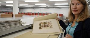 PRODUKTION - 17.08.2023, Brandenburg, Potsdam: Ilka Brombach, wissenschaftlich-kuratorische Leitung des Filmmuseums Potsdam, zeigt im neuen Archiv des Museums ein Szenenbild von Willi Depenau. Nach Abschluss des Umzuges der Bestände wird jetzt eine Ausstellung in den Räumen des Schaudepots vorbereitet, die im kommenden Jahr für Besucher geöffnet wird. (zu dpa: «Kamera-Kran im Atrium: Archiv und Schaudepot des Filmmuseums») Foto: Bernd Settnik/dpa - ACHTUNG: Nur zur redaktionellen Verwendung im Zusammenhang mit einer Berichterstattung über die Ausstellung und nur mit vollständiger Nennung des vorstehenden Credits +++ dpa-Bildfunk +++