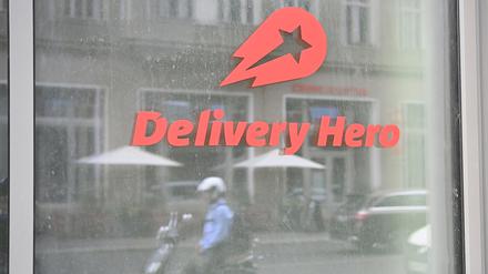 Ein Mopedfahrer spiegelt sich in einer Glasscheibe an der Zentrale des Essenlieferdienstes Delivery Hero.