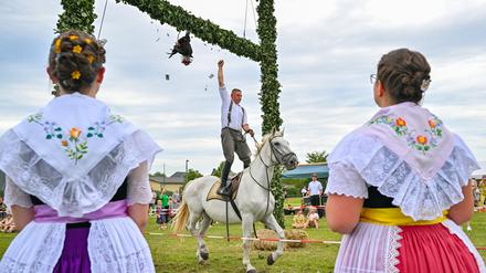 Ein Teilnehmer beim traditionellen sorbisch-wendischen Hahnrupfen beim Erntefest in Heinersbrück, versucht dem Hahn den Kopf abzureißen.