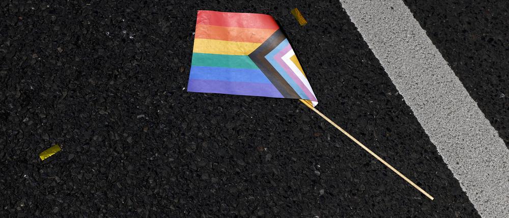 Eine Progressive Pride Flag liegt auf dem Boden.