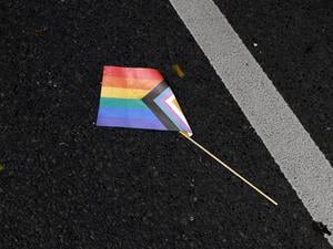 Eine Progressive Pride Flag liegt auf dem Boden. 