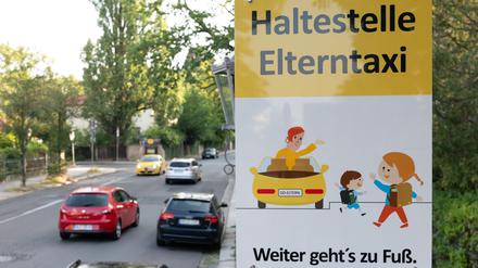 Ein Schild mit der Aufschrift „Haltestelle Elterntaxi“ steht vor einer Grundschule.