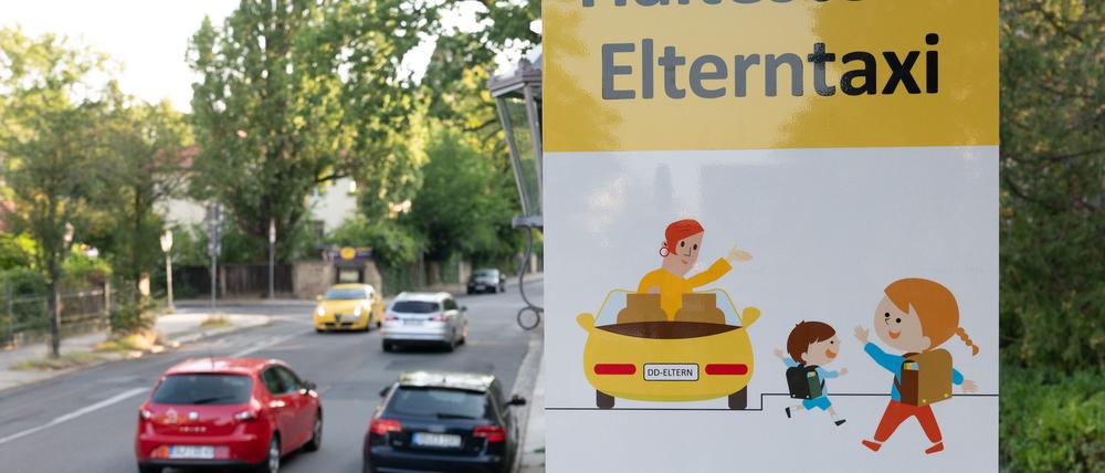 Ein Schild mit der Aufschrift „Haltestelle Elterntaxi“ steht vor einer Grundschule.