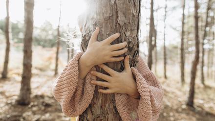 Girl hugging tree trunk in forest