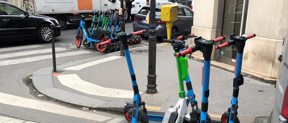 E-Scooter von drei verschiedenen Anbietern stehen auf einem dafür vorgesehenen Parkplatz in Paris.