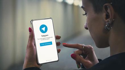 Eine junge Frau startet Telegram auf dem Smartphone.