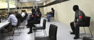 Glasbox im Gerichtssaal: bewacht von vermummten Polizisten.